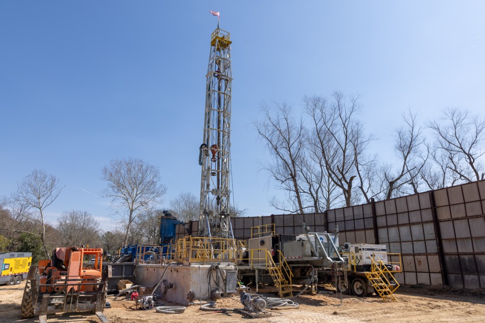 Water well drilling rig setup behind the temporary sound barrier wall.