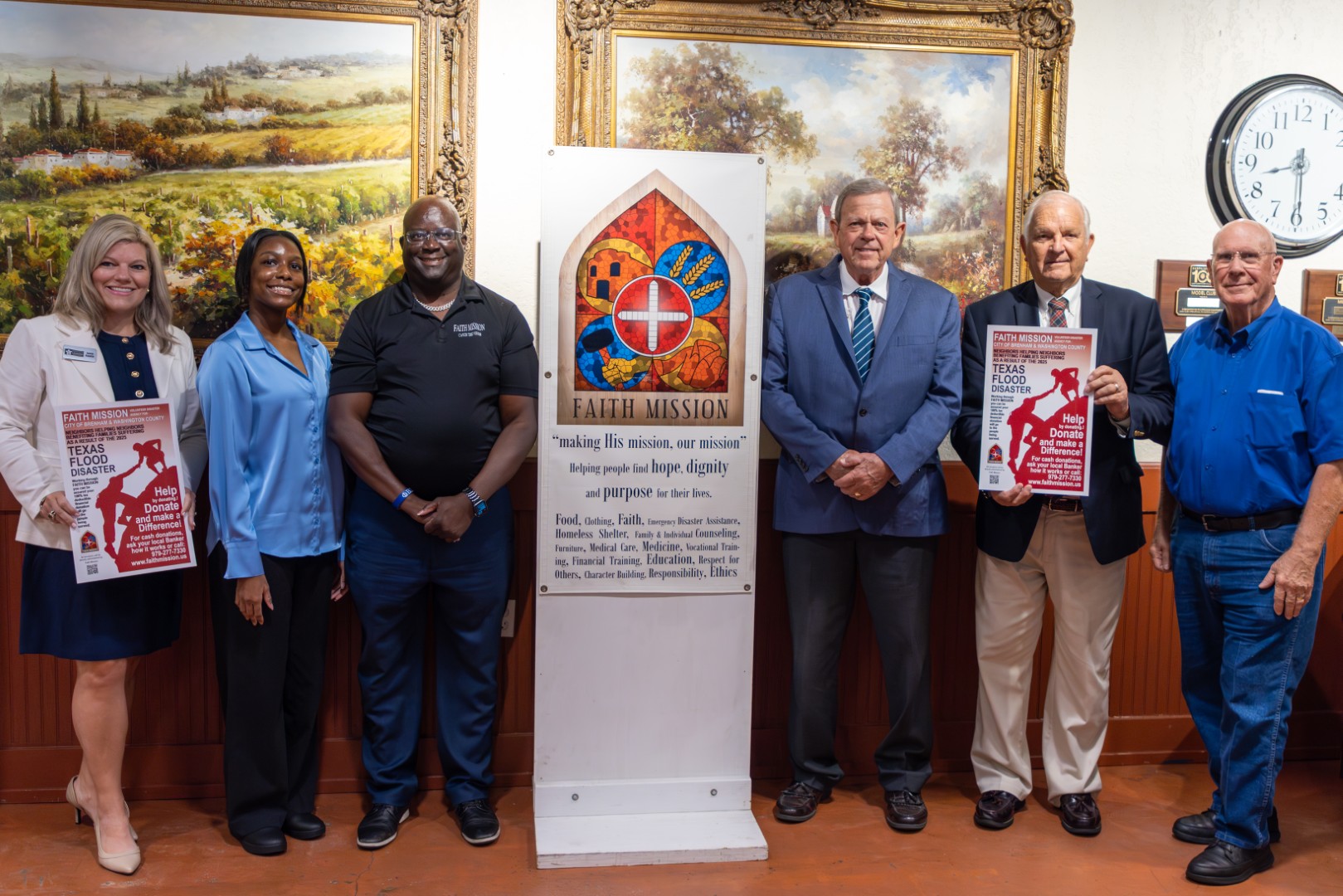 Representatives from the Washington County Chamber of Commerce, State Senate, Faith Mission, Washington County, and the City of Brenham pose with a donation poster instructing how to help those affected by the Texas Flood Disaster