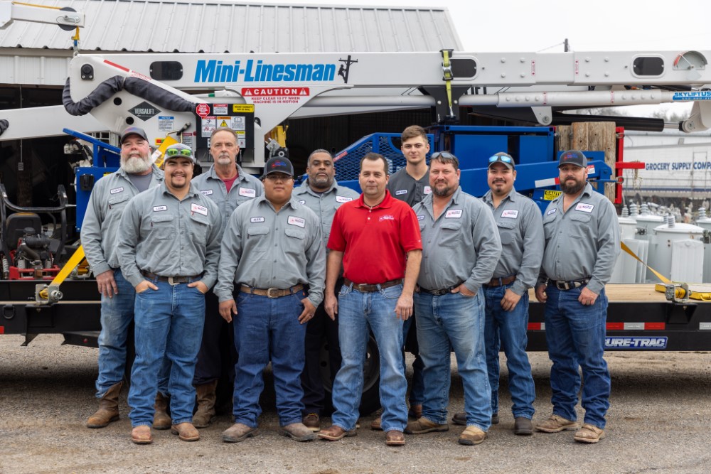 Ten Electric staff members in front of a lift machine