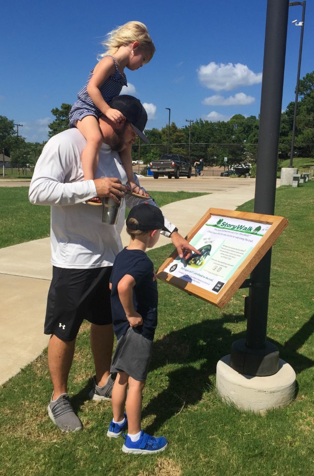 Family reading a StoryWalk board in fireman's park