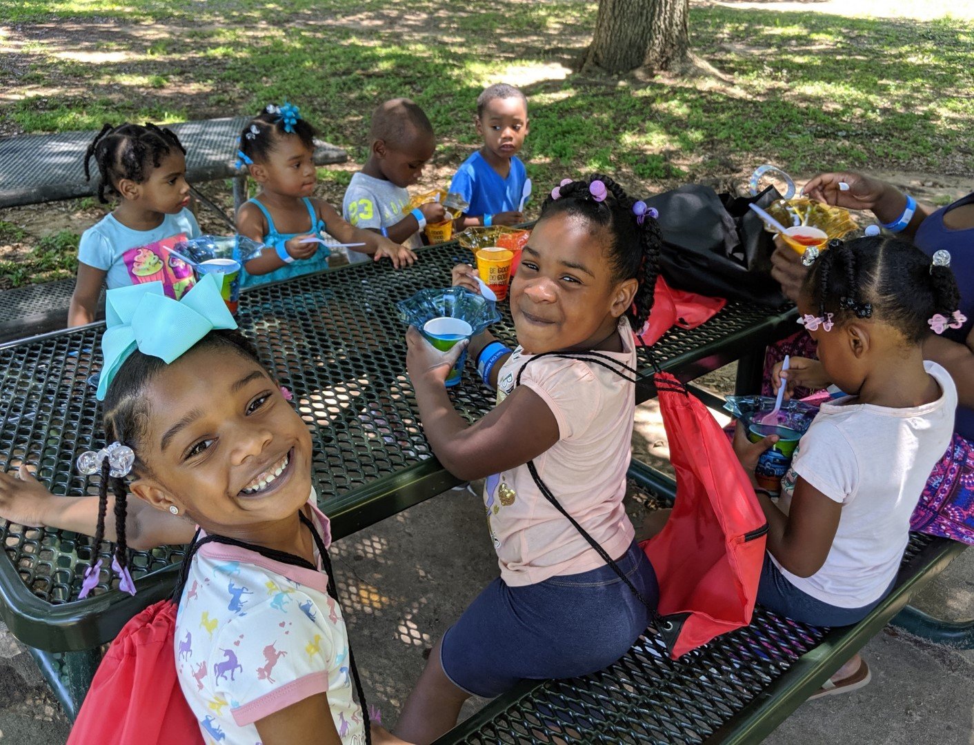 a group of kids enjoying snow cones at a picnic table in the shade at Jackson Street Park