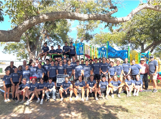 BISD baseball and softball players pose for a group picture after donating their time assisting WoodmenLlife  give back to the community at Henderson Park