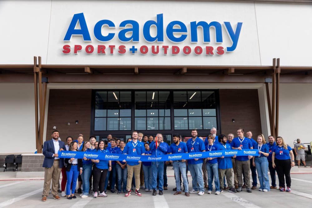 Academy Sports + Outdoors staff standing in front of store cutting ribbon