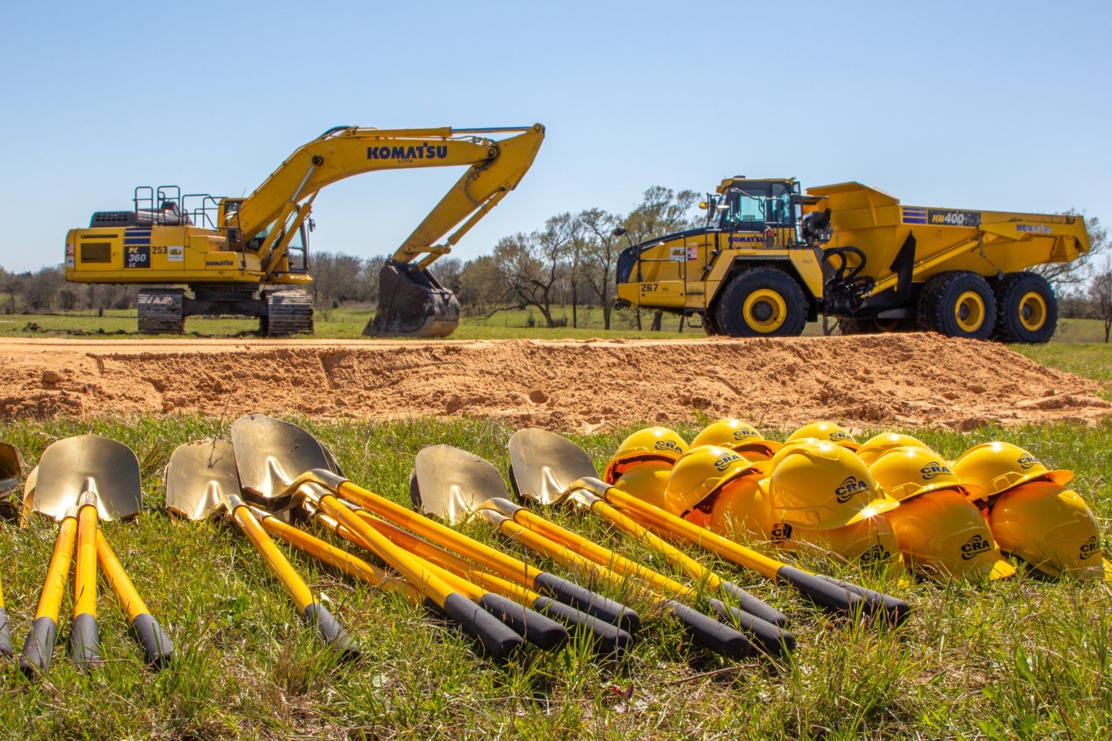 shovels and hard hats in front of earth moving equipment