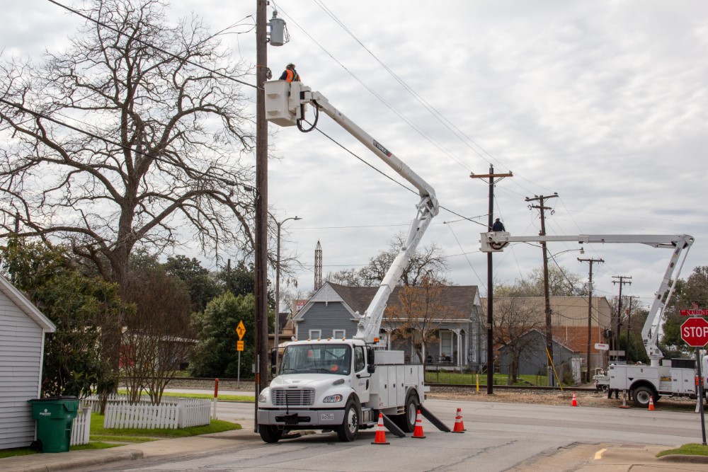 Electric Lineman installing fiber optic cable on utility pole in a bucket truck